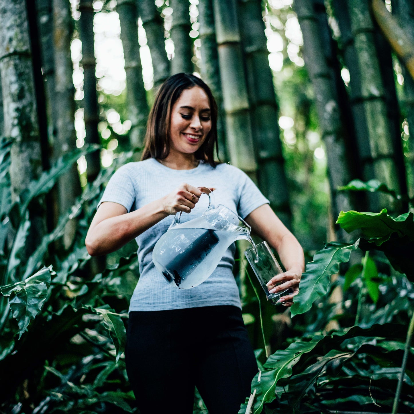 Lady pouring glass of charcoal filtered water from a glass jug